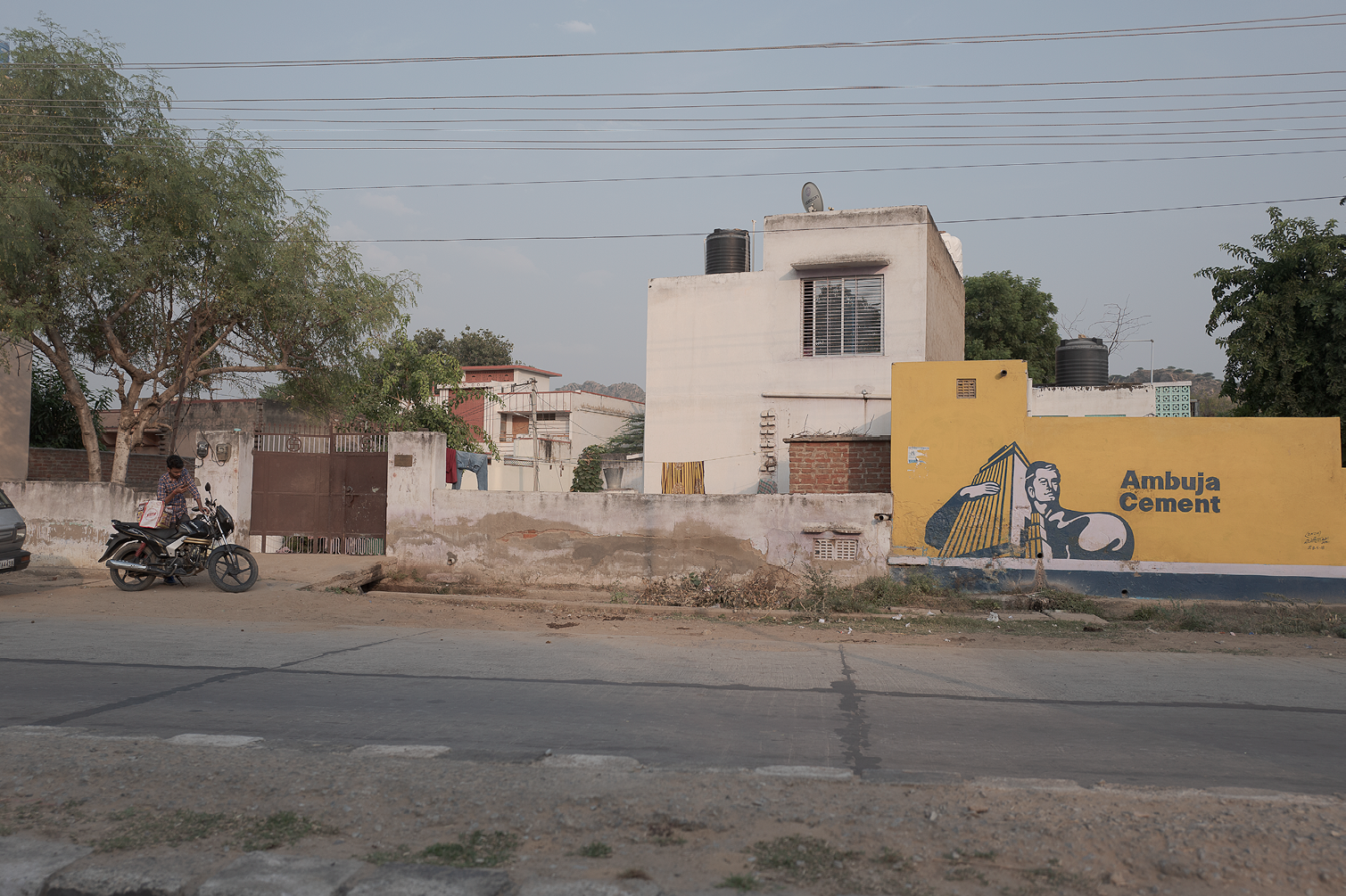 Un mur avec une peinture murale représentant une femme portant une caisse en bois, avec le texte "Ambuja Cement" à côté.