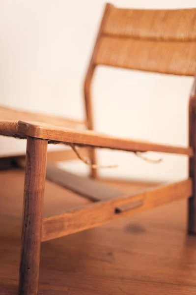 Chaise en bois avec un siège en toile, vue de côté.