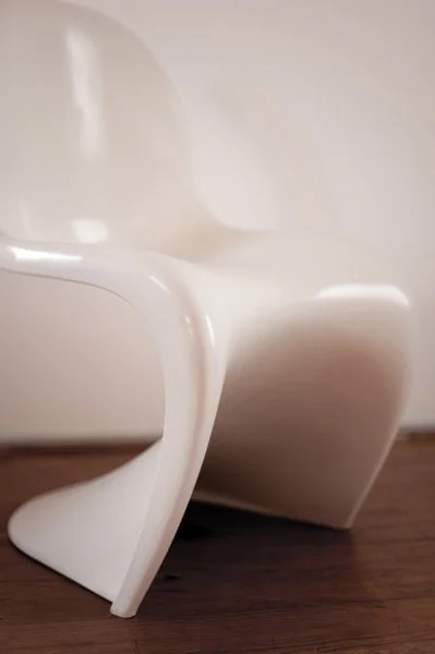 Chaise blanche moderne en plastique sur un sol en bois.