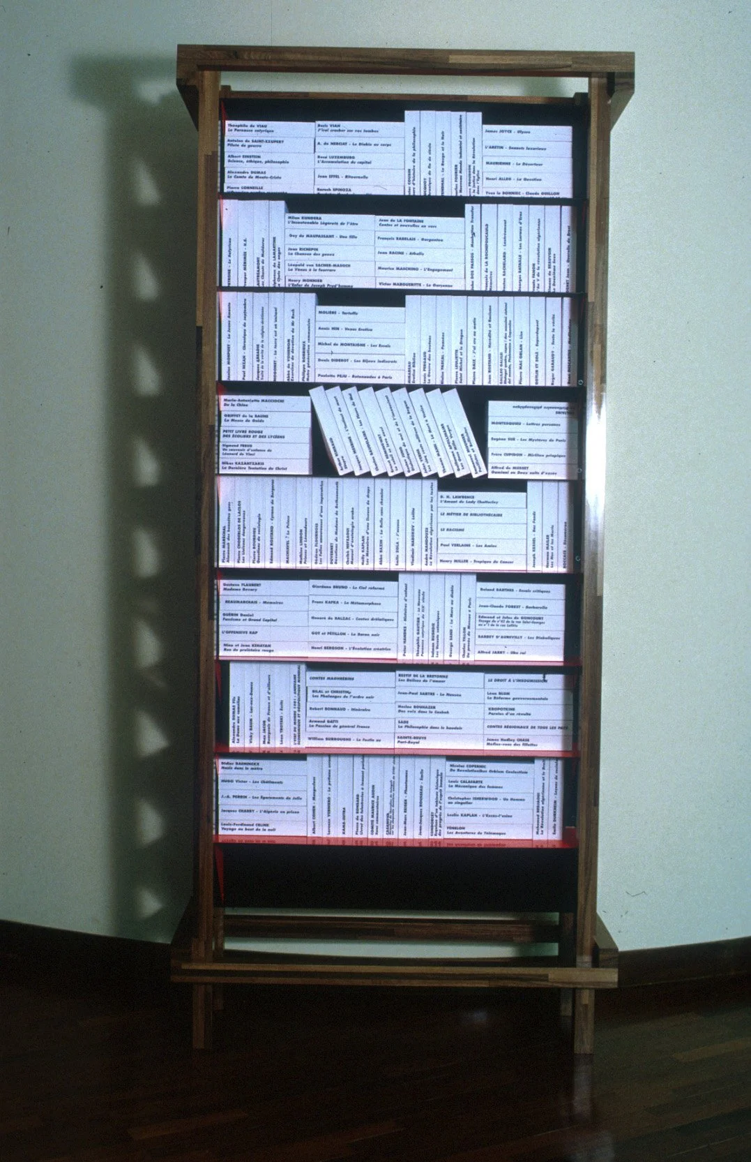 Un tableau avec plusieurs cartes postales ou documents affichés verticalement dans une structure en bois.