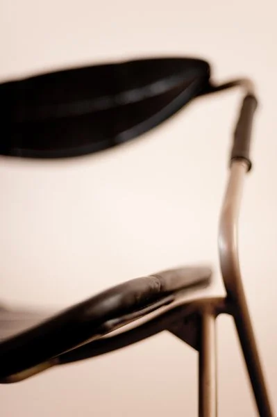 Chaise avec siège en cuir noir et structure en bois ou métal.