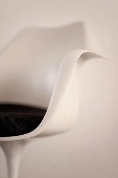 Une chaise blanche avec un design moderne et courbé, vue de côté, contre un fond blanc.