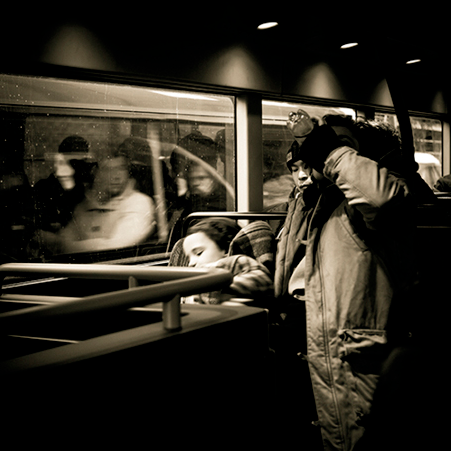 Trois personnes endormies debout dans un bus, en noir et blanc.