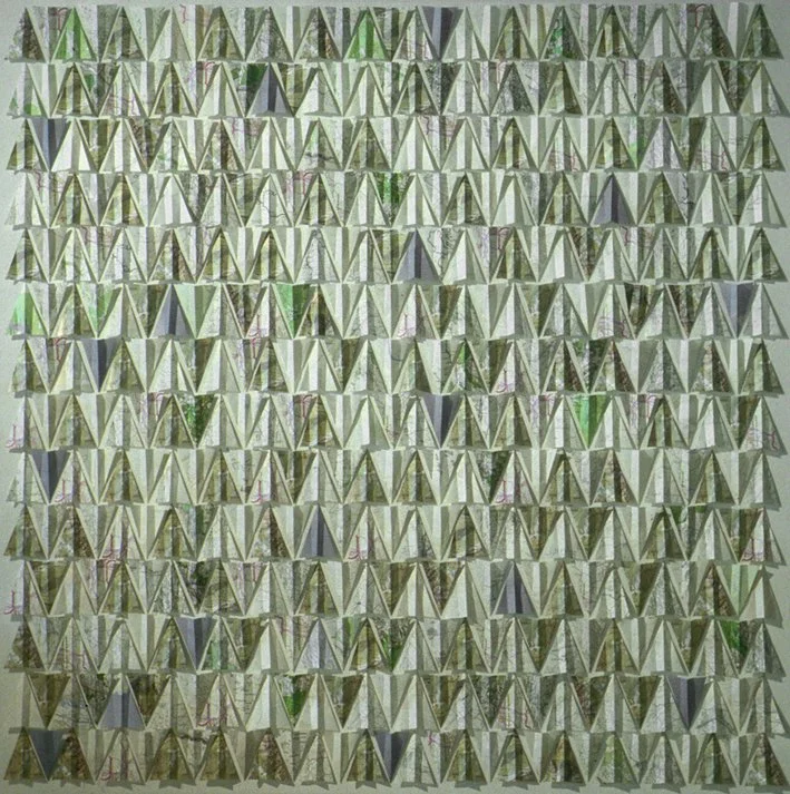 Une mosaïque géométrique composée de triangles et de formes en V, principalement en nuances de vert, gris et beige.
