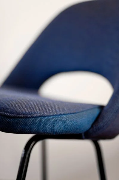 Chaise bleue avec un siège rembourré et des jambes en métal noir.