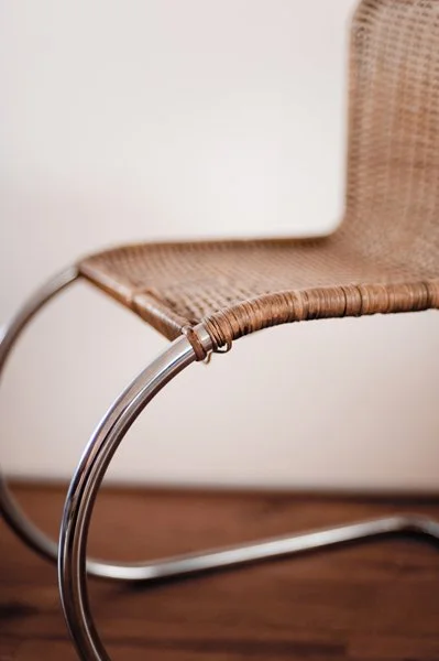 Chaise moderne en rotin avec cadre en métal incurvé dans une pièce avec un sol en bois.