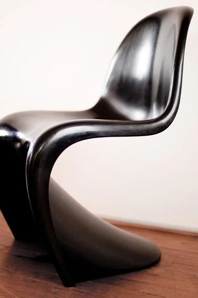 Chaise en plastique noir sur un sol en bois clair.