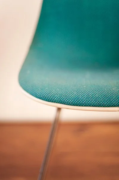 Une chaise moderne avec un siège en tissu vert et des pieds en métal.