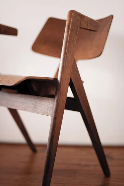 Chaise en bois vue de côté, avec un design classique et minimaliste, placée sur un sol en bois clair.