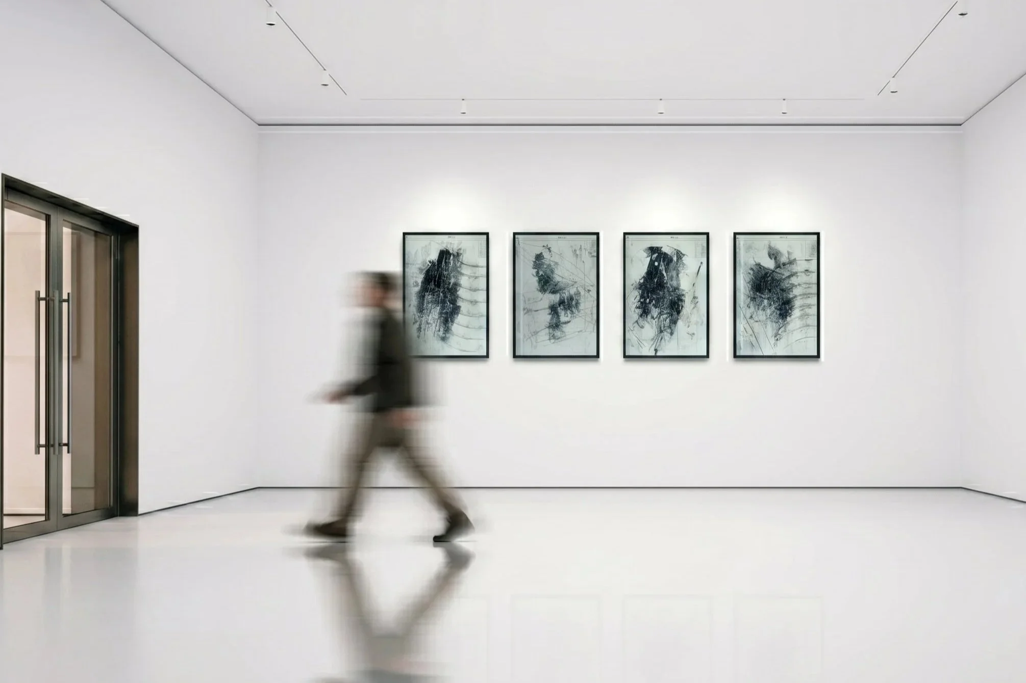 Une personne marchant dans un musée blanc avec quatre œuvres d'art abstrait encadrées sur le mur.