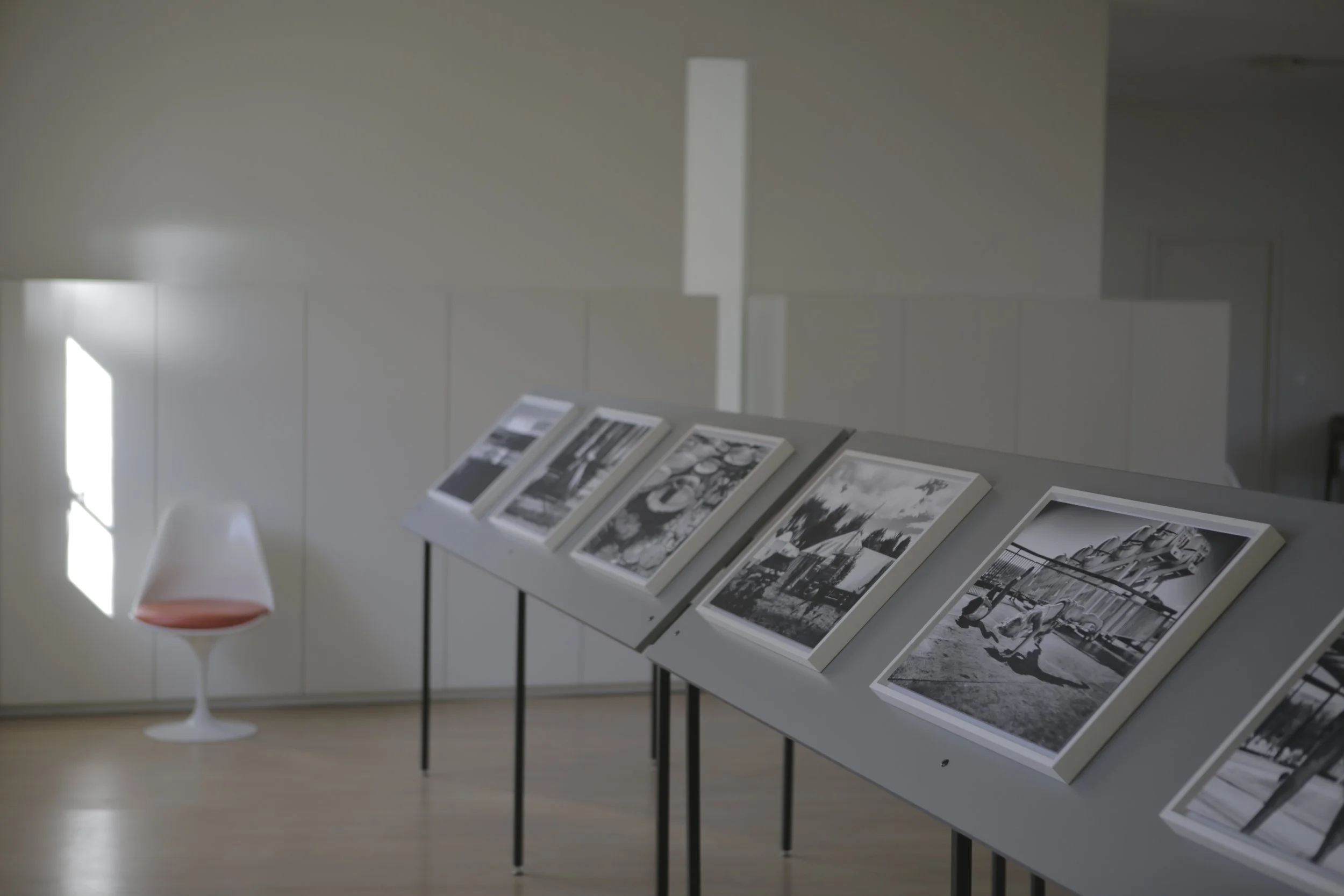 Exposition de photos en noir et blanc sur un présentoir en intérieur, avec un mur blanc en arrière-plan.