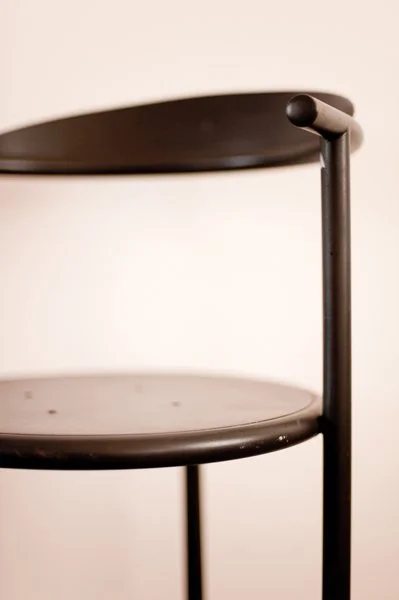 Une table d'appoint noire avec deux surfaces rondes, une en haut et une en bas, soutenues par une structure en métal.
