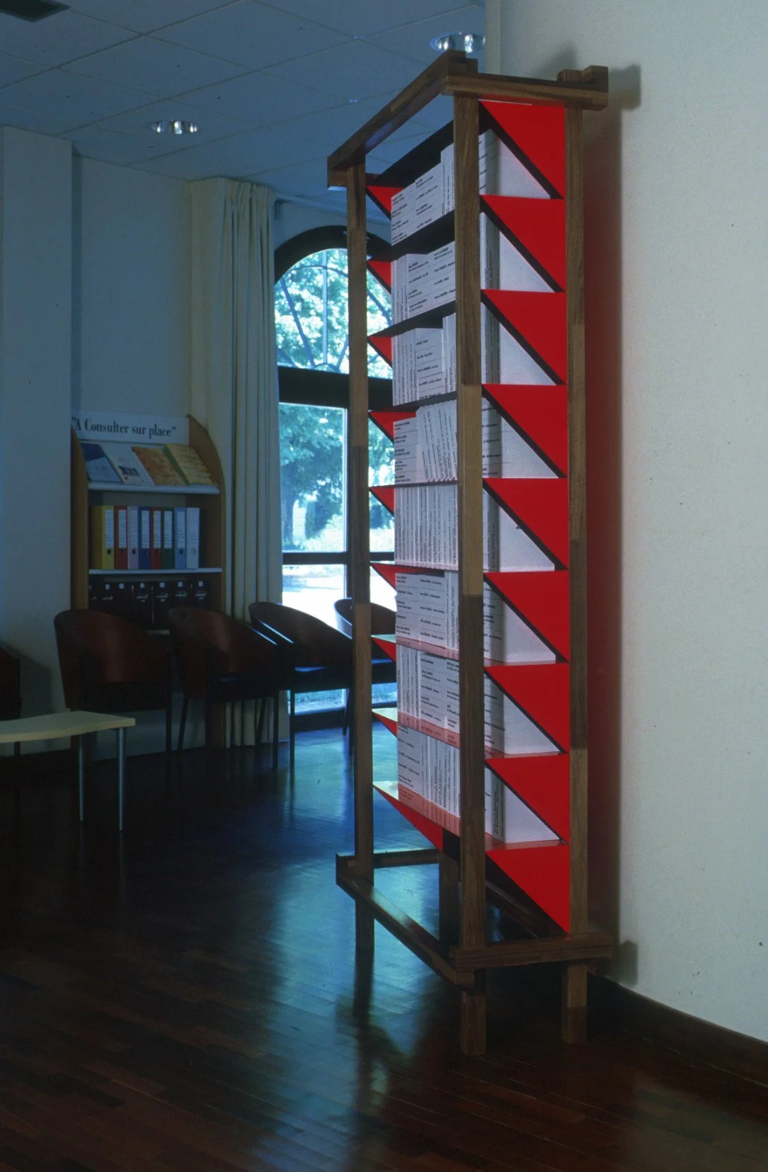 Statue en bois avec plusieurs documents ou affiches ou textes dans la bibliothèque ou salle d'attente.