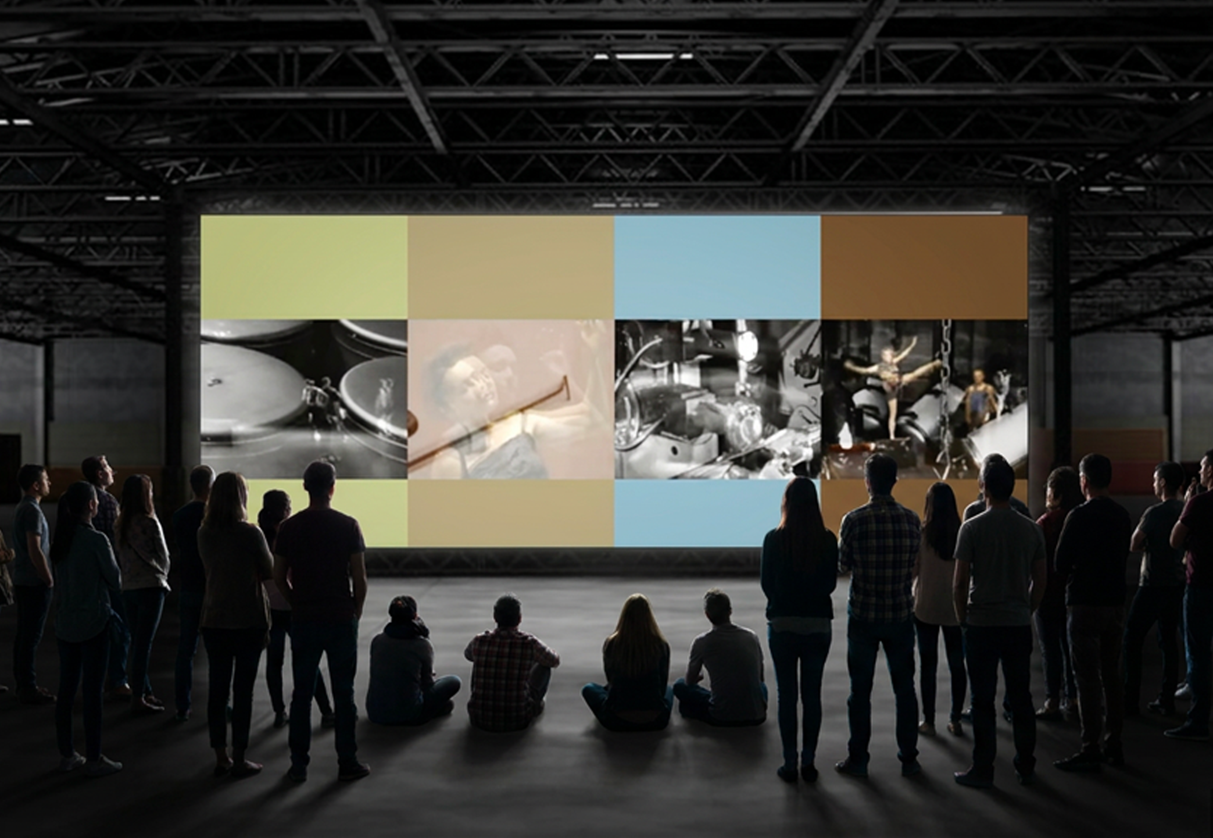 Public réunie dans une salle d'exposition regardant un grand écran présentant des images de cuisine et de design.