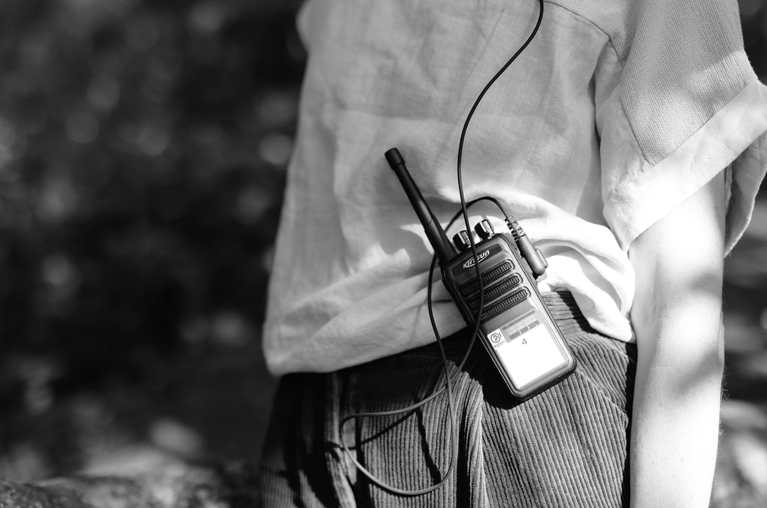 Close-up of a person wearing a light-coloured shirt with an event radio.