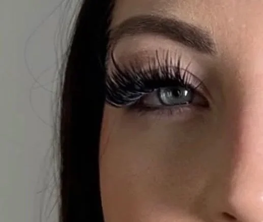 Close-up of a woman's eye with long eyelashes and brown eyebrow.