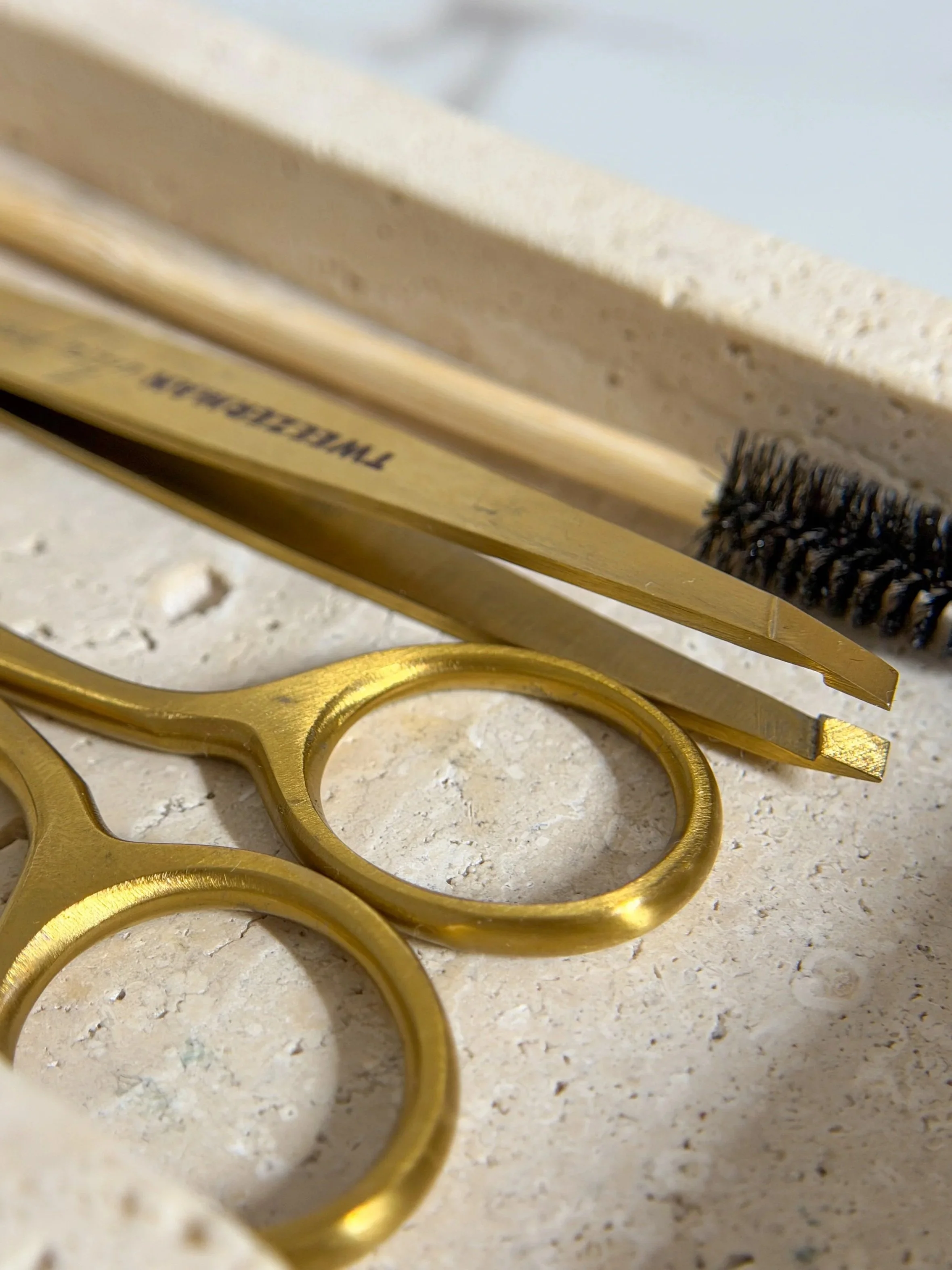Close-up of a golden brass knuckle and a tool with a metal brush, resting on a speckled surface.