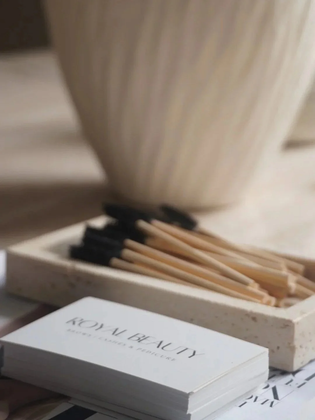 A stack of booklets titled "Royal Beauty" with a subtitle about luxury planet and beauty, placed next to a box of matches with black tips, partially visible, and blurred background.