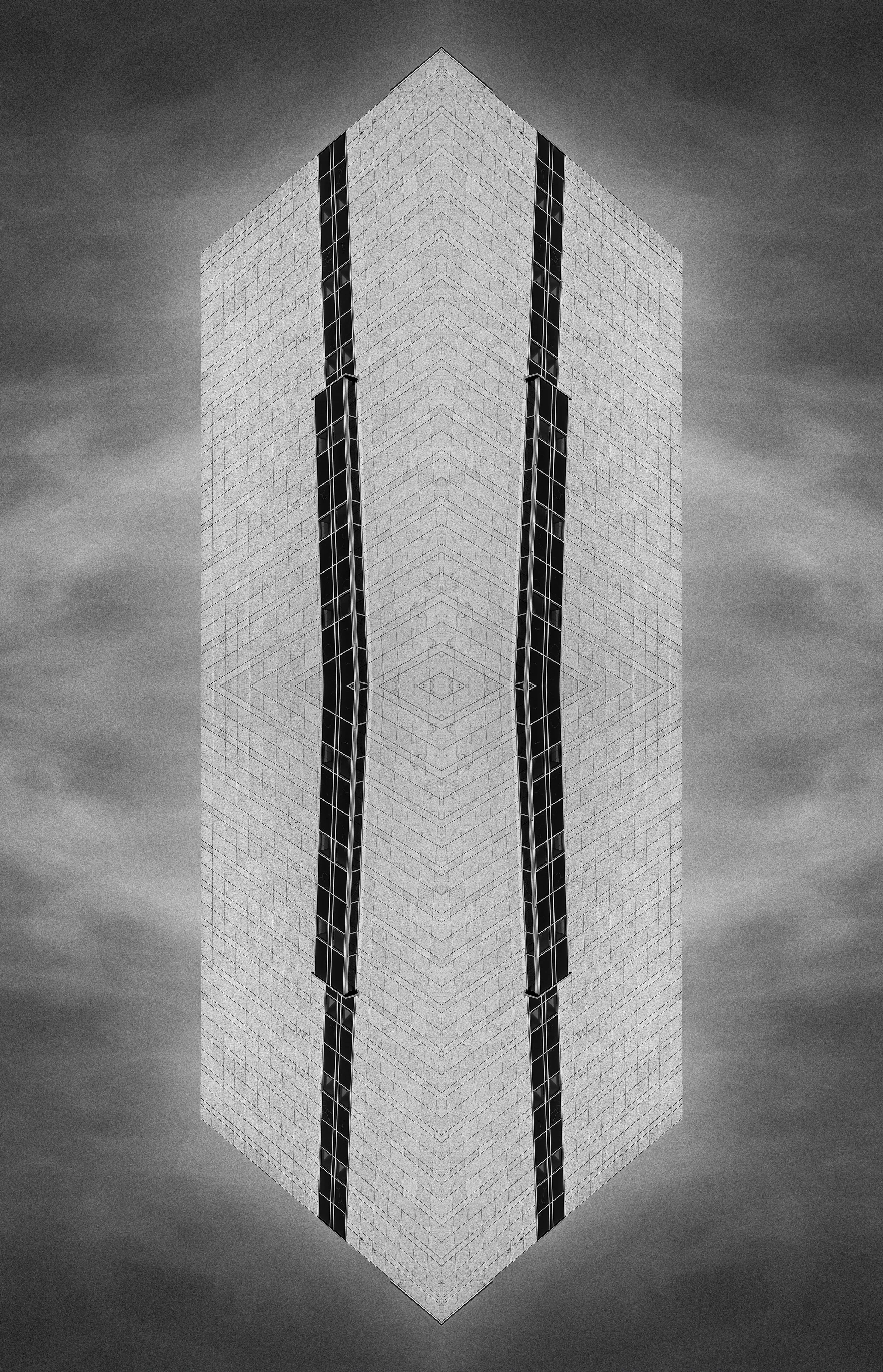 A black and white photo of a modern skyscraper with reflective windows and a unique angular design, viewed from a low angle against a cloudy sky.