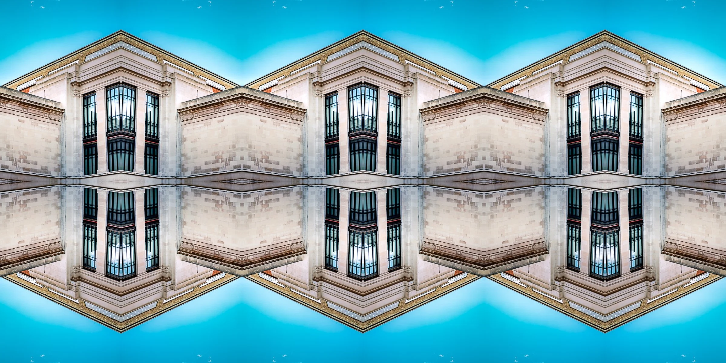 A mirrored image of a building with tall windows and limestone facade, reflecting a blue sky.