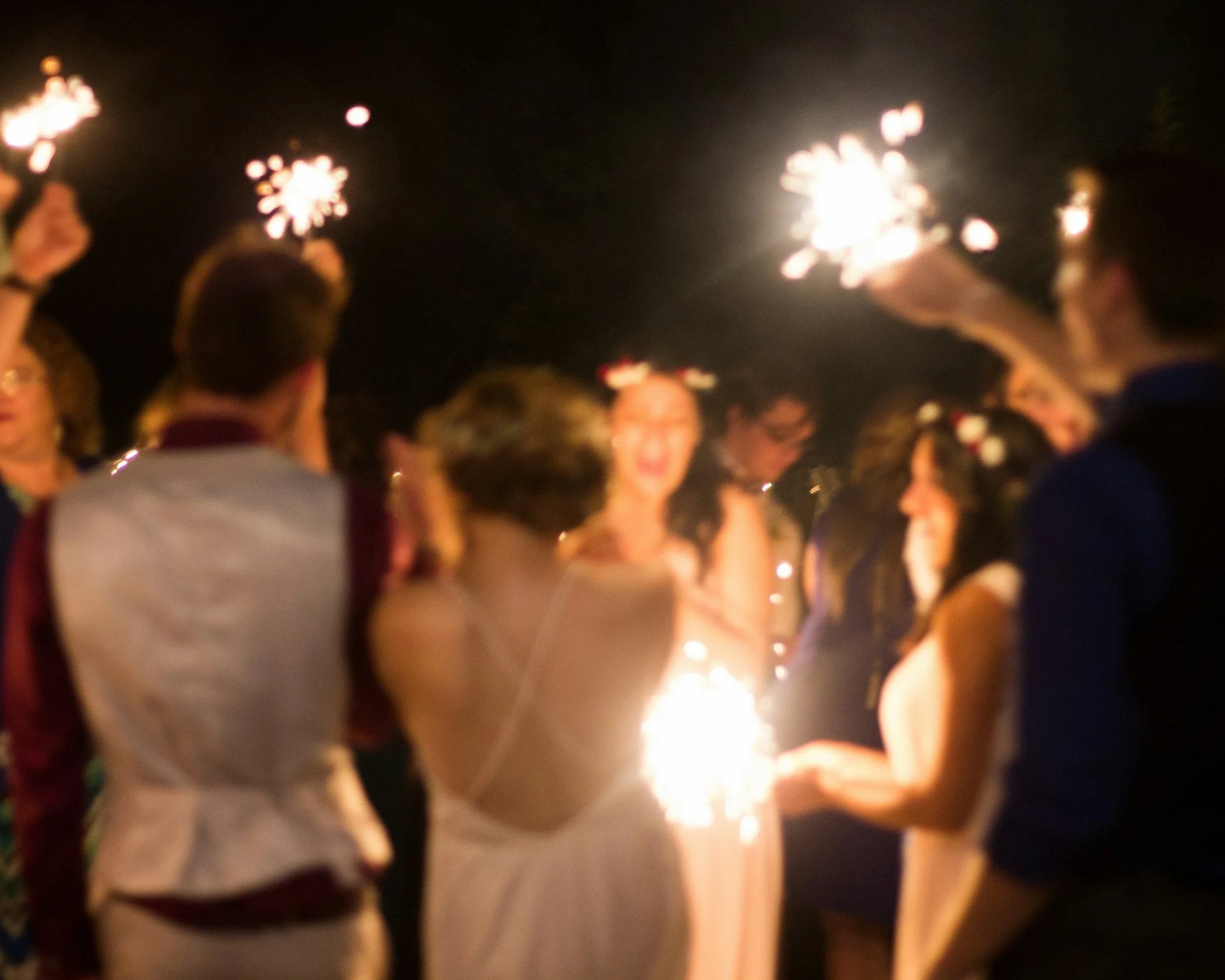 People holding sparklers at night, celebrating with a group of friends.