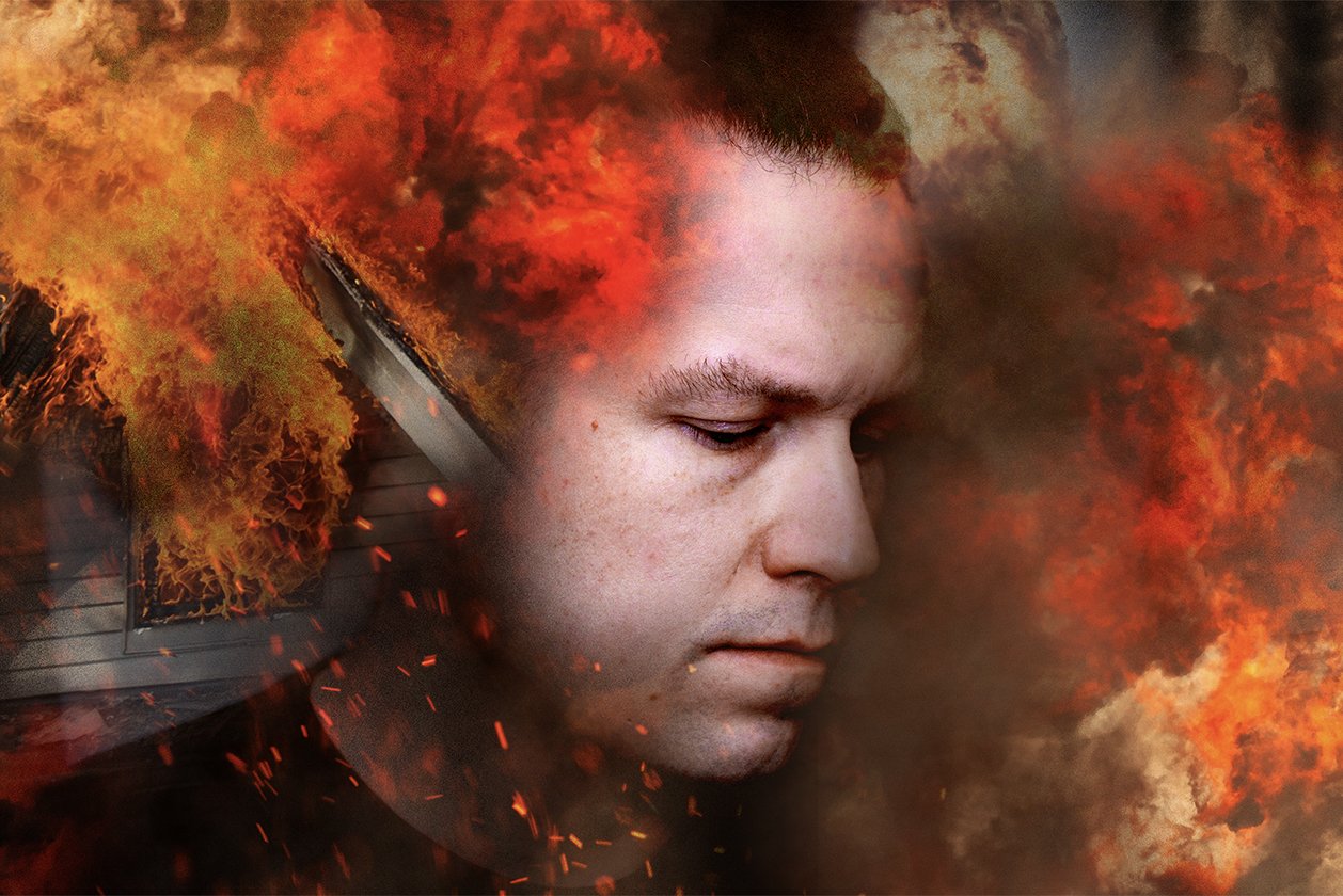 A young man with a serious expression is surrounded by flames and smoke, creating a fiery and intense scene.