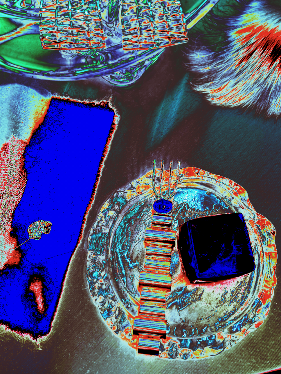 Color-inverted image of a kitchen table with various objects including a black square item, a blue tray, a fork, a circular dish, a rectangular object with color stripes, and a pair of cylindrical wire containers.