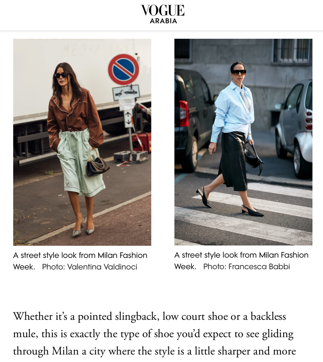 Two women in fashionable outfits walking in an urban environment. Left woman wears a brown shirt, mint green pleated skirt, and sunglasses. Right woman wears a light blue shirt, black leather skirt, high-heeled shoes, and sunglasses. Both carry handbags.