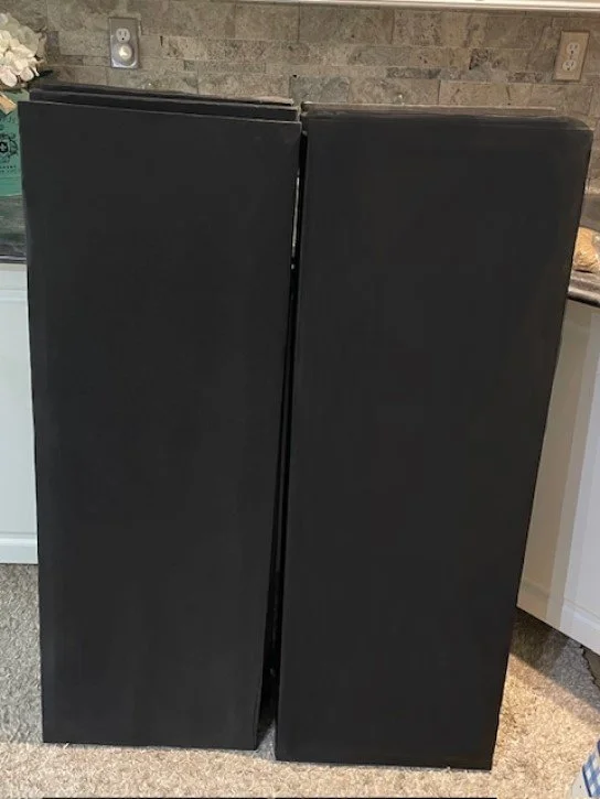 Two stacks of black sound proofing panels standing side by side infront of counters & A brick backdrop.