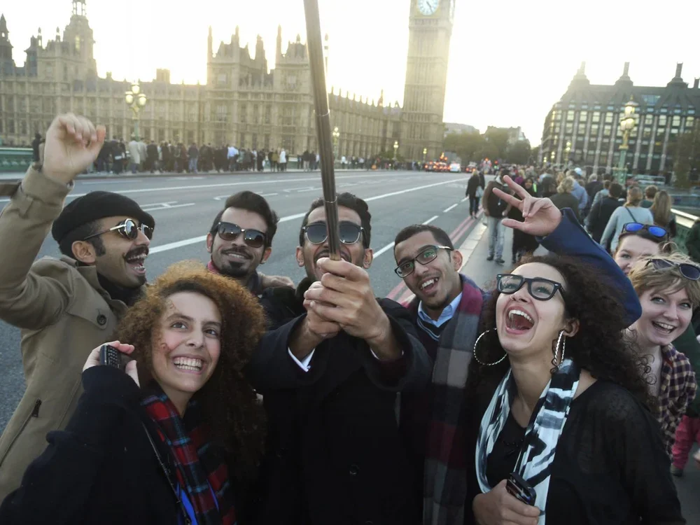 Group of diverse friends taking a selfie in front of the Houses of Parliament and Big Ben in London, England during the daytime.