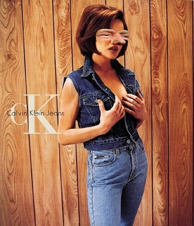 A woman with manipulated facial features, including exaggerated lips and eyes, standing against a wood-paneled wall. She is wearing a sleeveless denim vest and high-waisted jeans, holding her chest with one hand, in front of a Calvin Klein advertisem