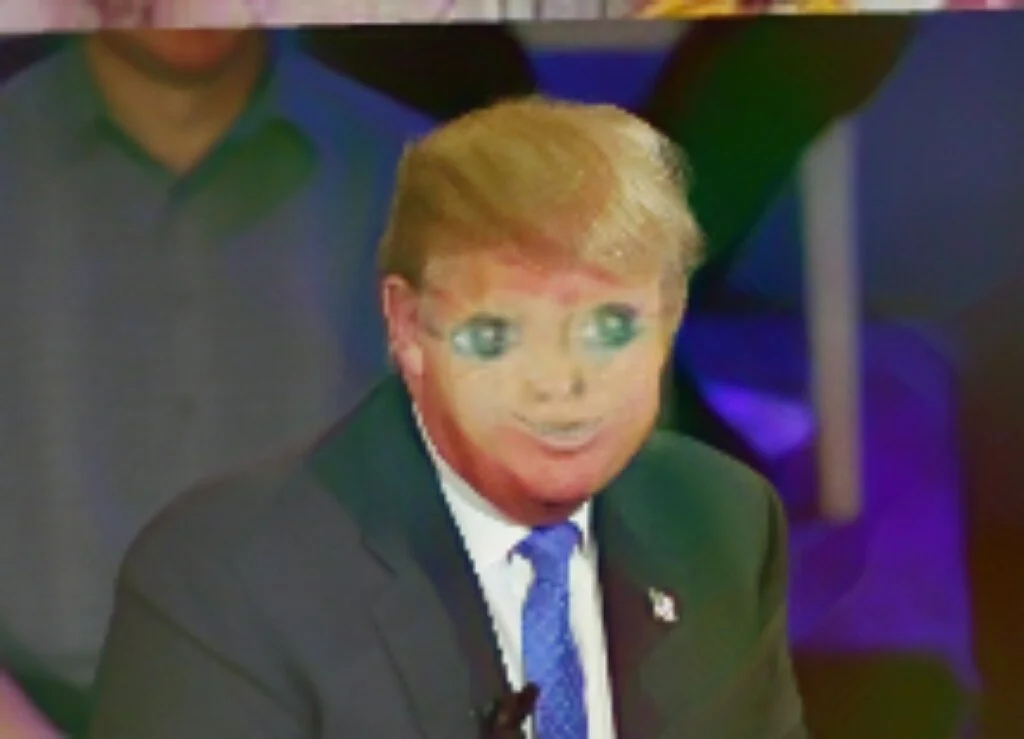A man with a suit and tie, with cartoonish, exaggerated facial features, seated in a colorful, possibly television studio setting.