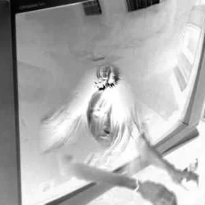 A person with long hair taking a selfie with their phone in a mirror.