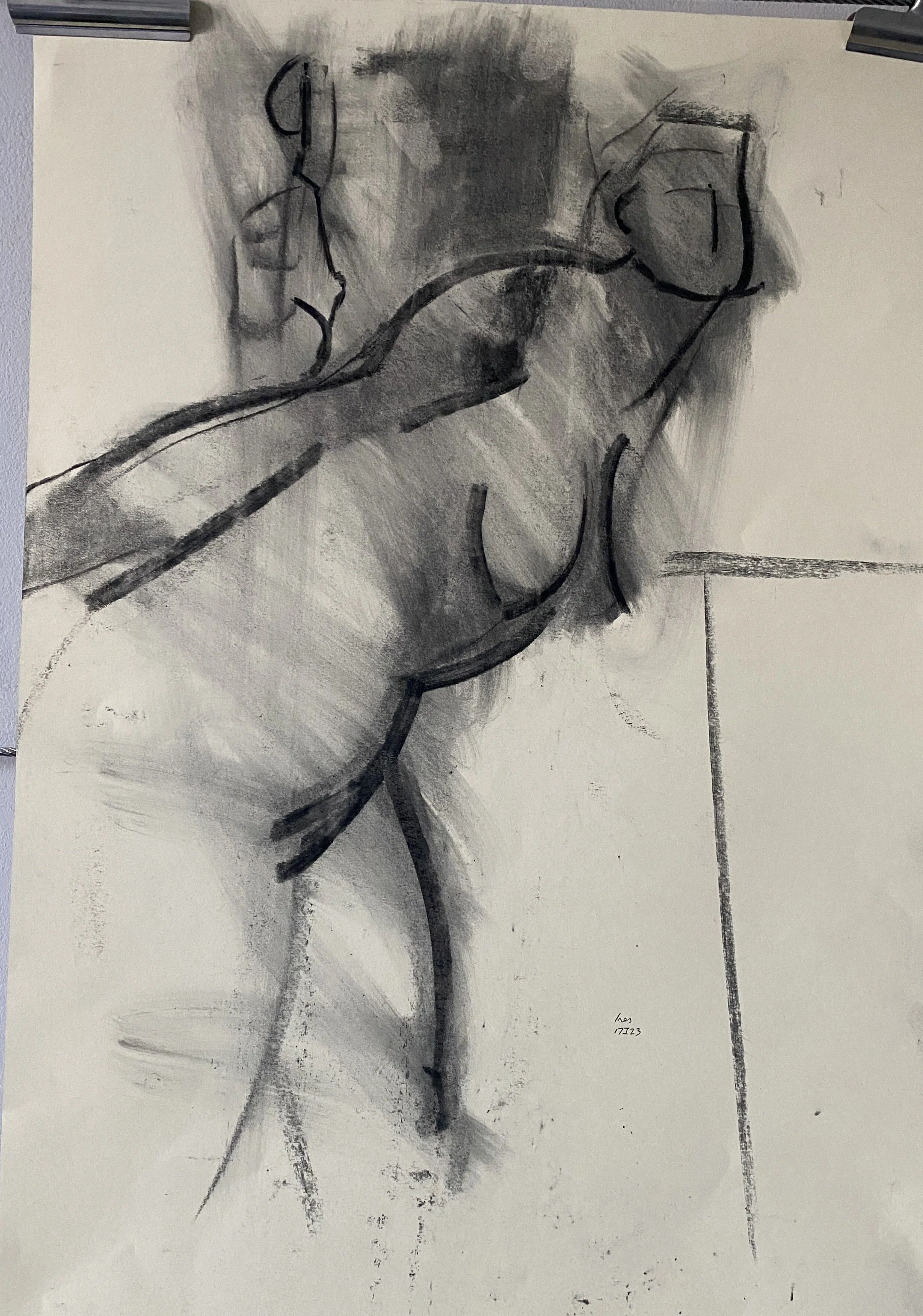 A black and white charcoal sketch of a reclining nude woman, viewed from above, on a textured surface with a marked line indicating the edge of a floor.