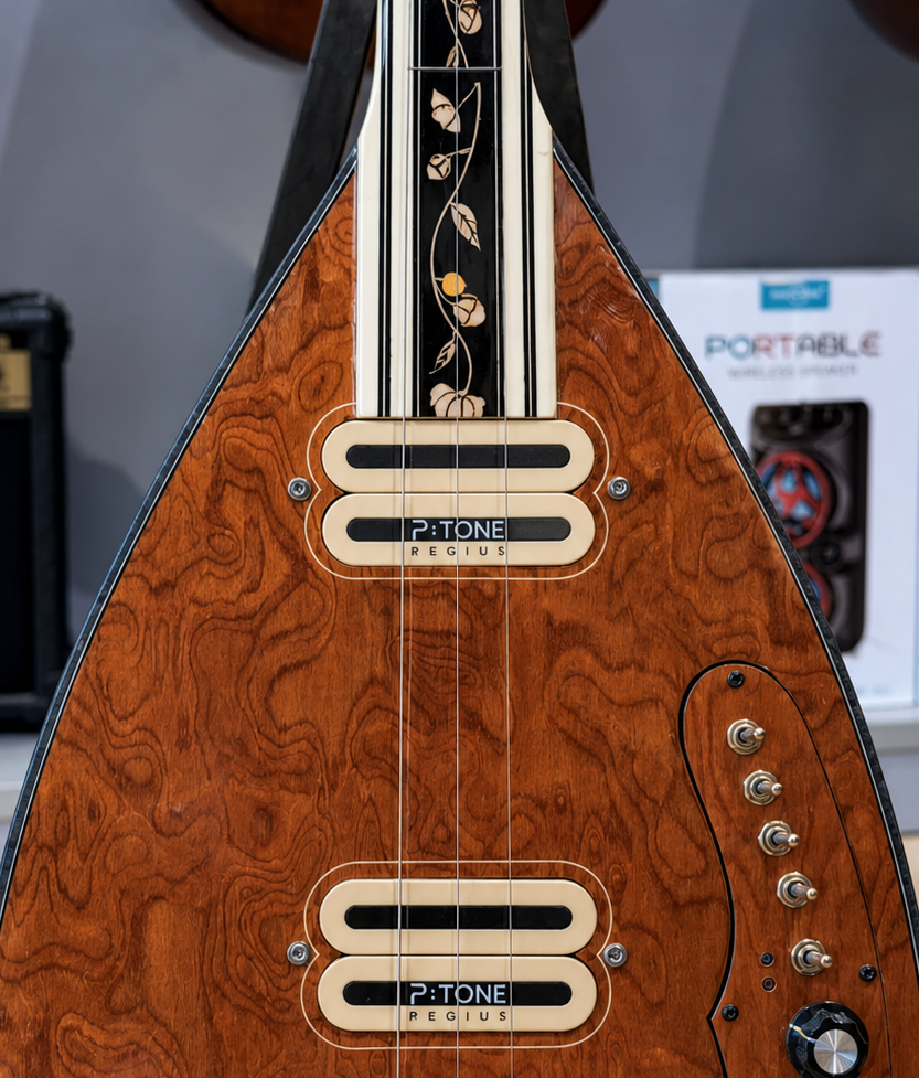 Close-up of a vintage-style electric guitar with a wooden finish and decorative inlay on the neck, featuring multiple control knobs and pickups labeled 'P-TONE REGIUS'.