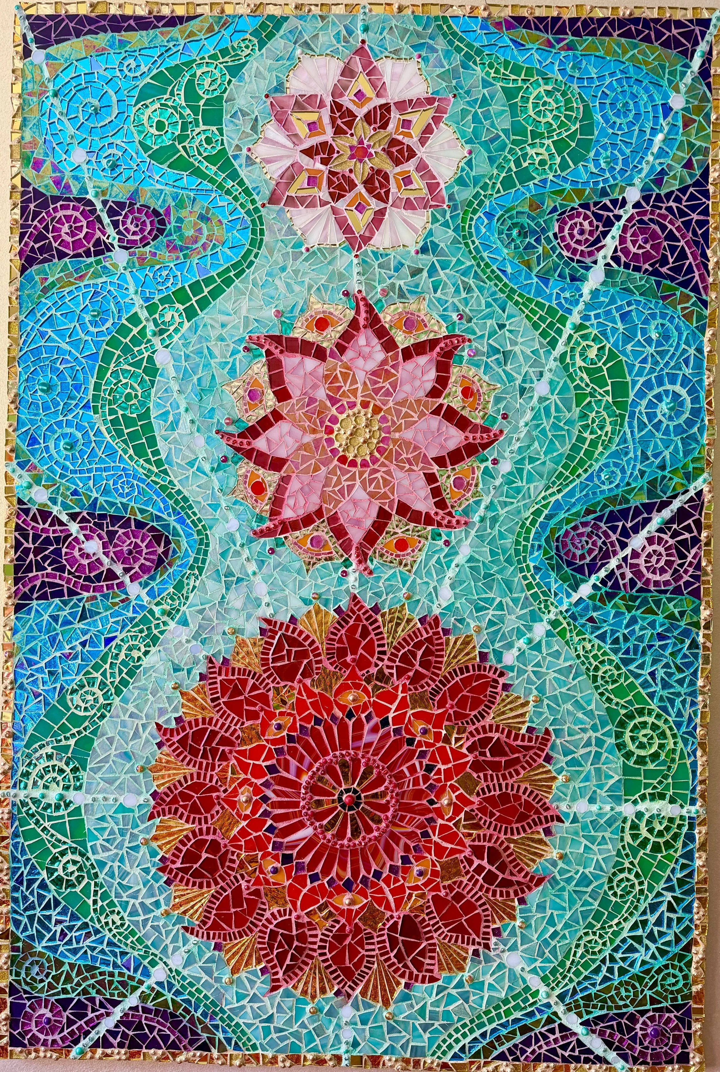 Colorful mosaic artwork featuring pink, red, purple, and green floral patterns with swirling green vines and a border of gold pieces.