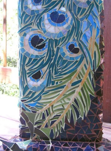 Colorful mosaic mural of leaves and flowers on a pillar.