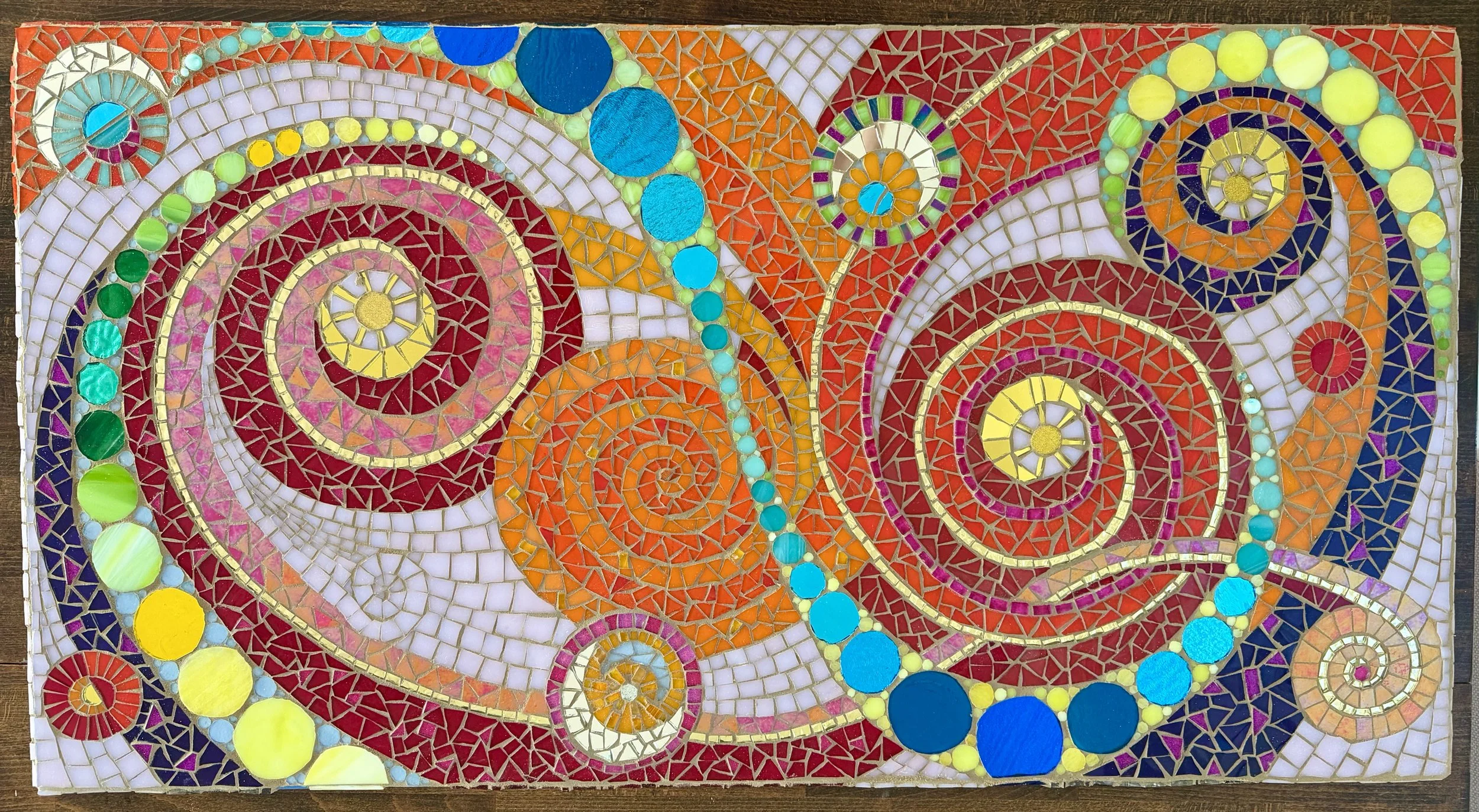 Colorful mosaic artwork featuring swirling patterns, circles, and spirals in various bright colors such as red, yellow, blue, orange, green, and purple.