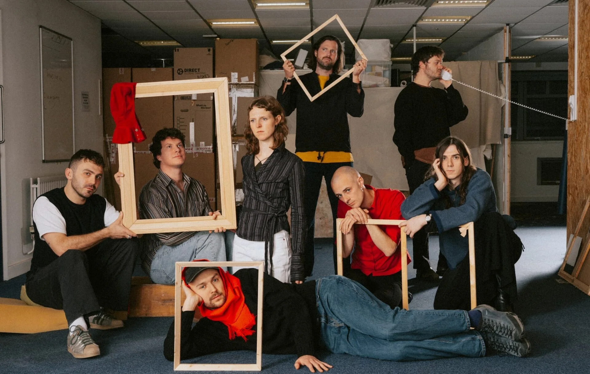 The band Caroline posing with empty picture frames and a telephone