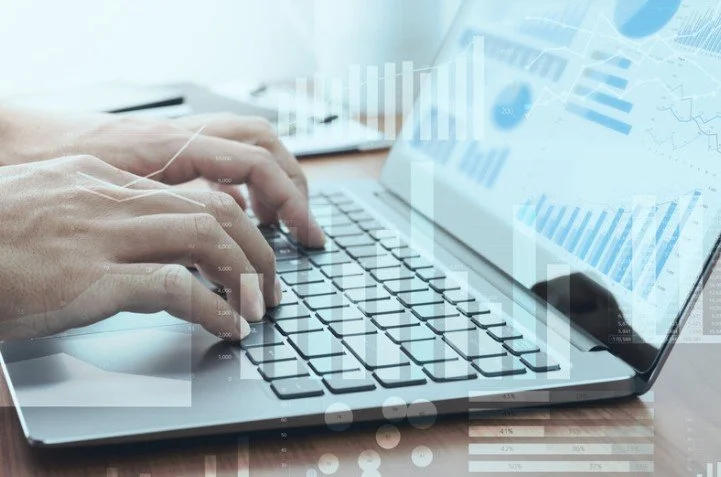 Person typing on a laptop with financial graphs,  data overlays, automations, and workflows.