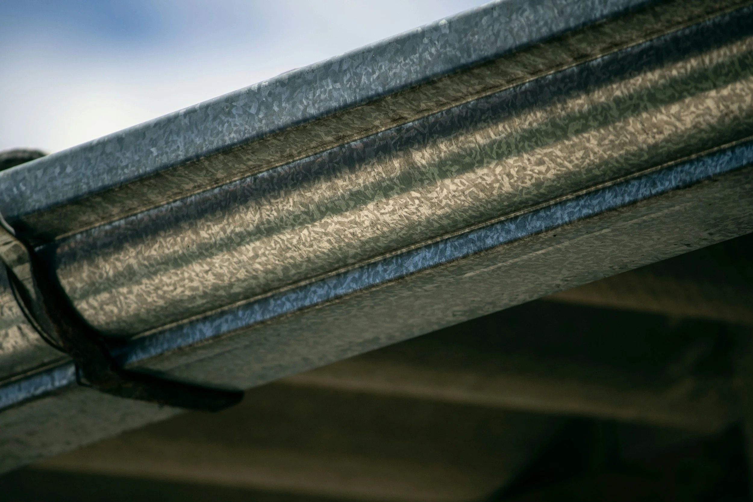 Close-up of a metallic razor blade with a textured surface, showing multiple blades, against a blurred background.