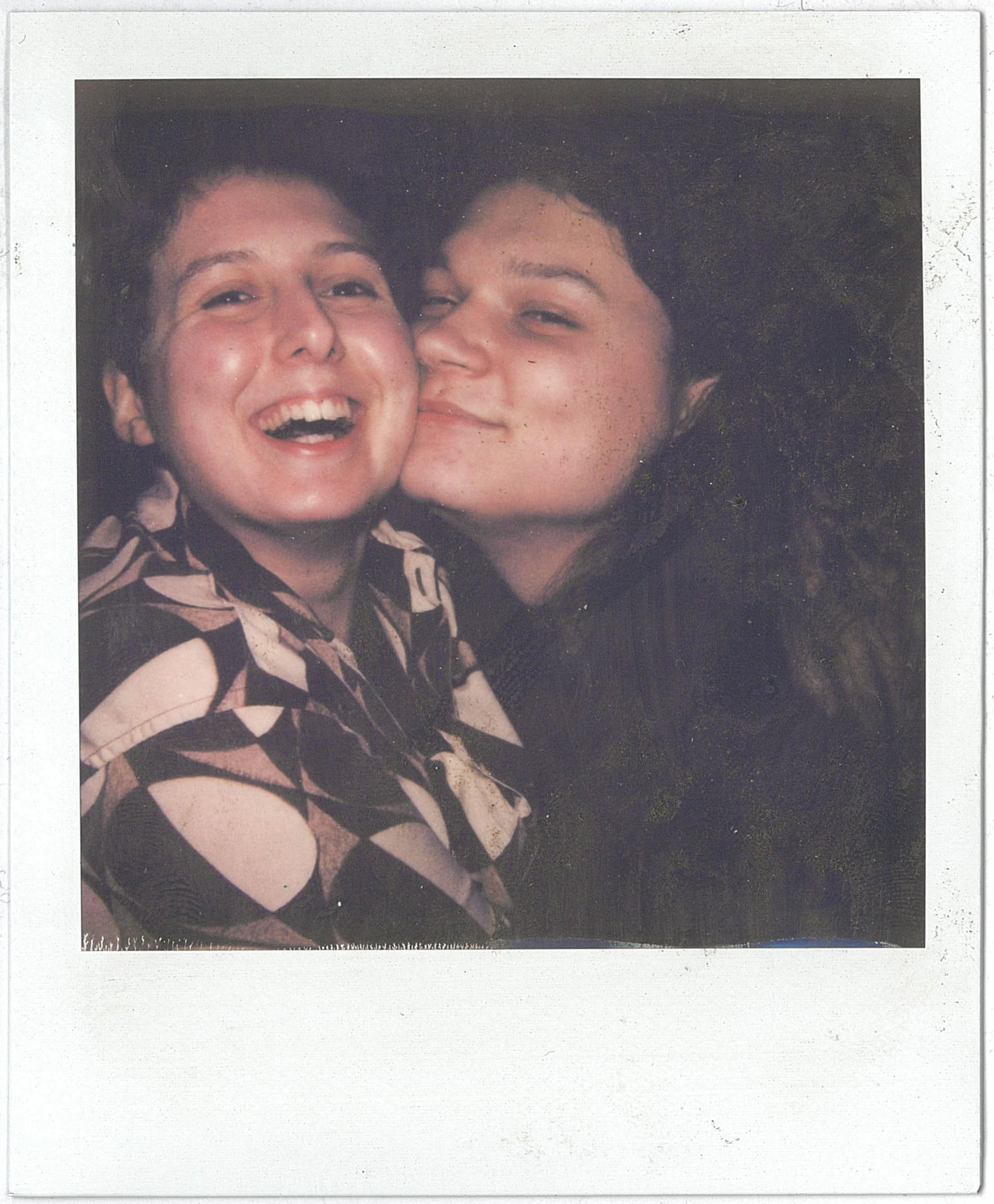 A Polaroid photograph of two people close together, smiling and enjoying each other's company.