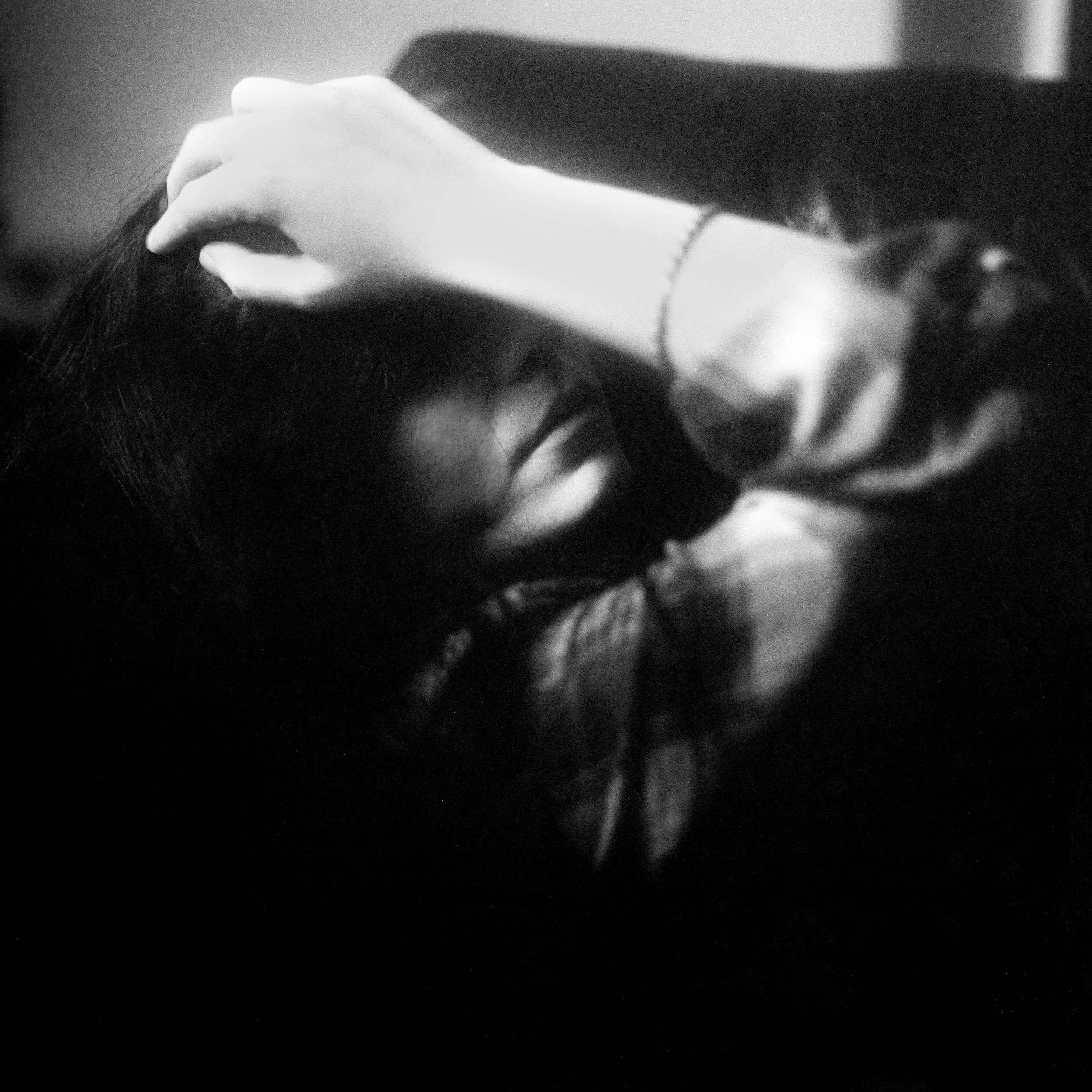 Close-up black and white photo of a person's hand holding a strand of dark hair.