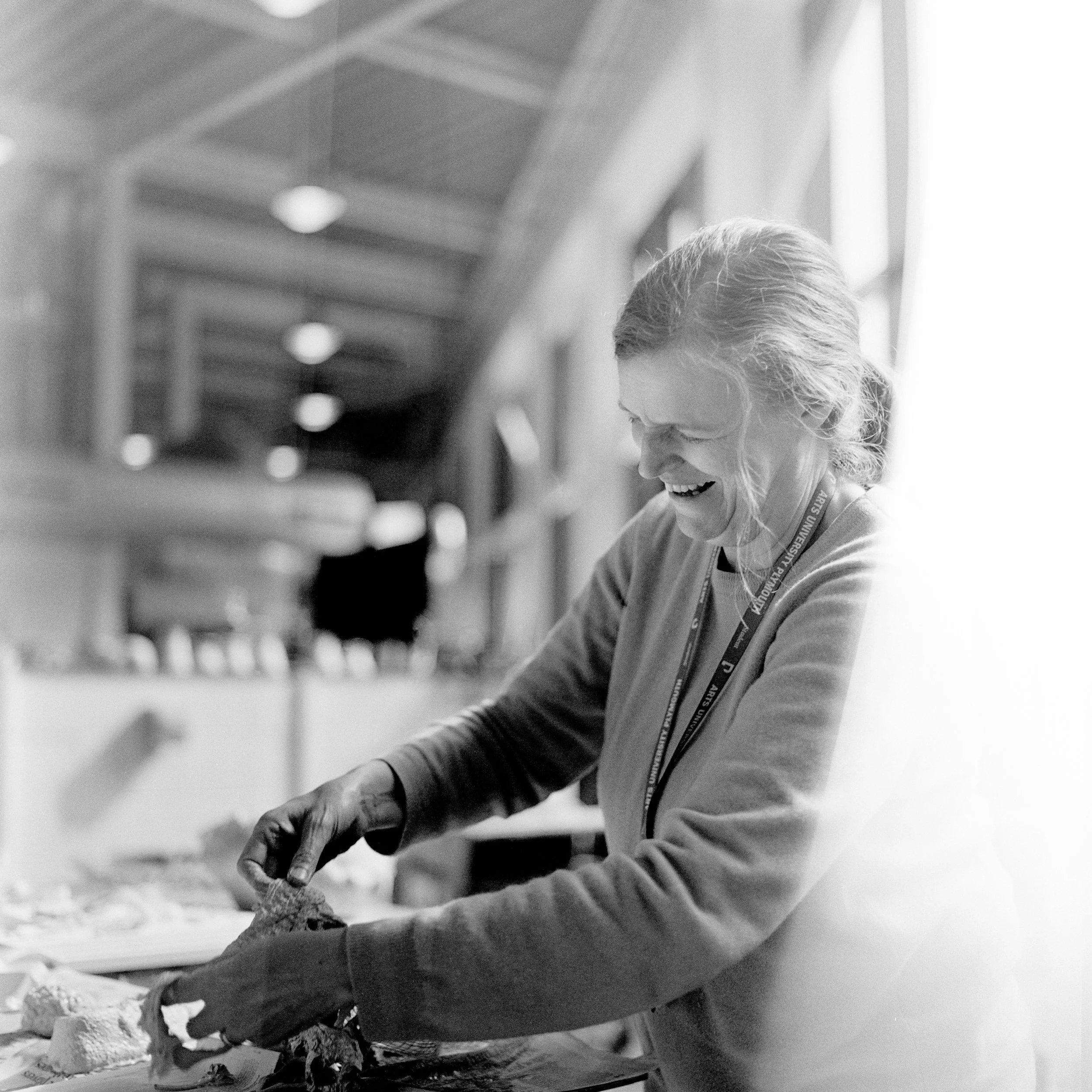 A woman smiling and working on an outdoor project, possibly building or crafting, with materials and tools around her.