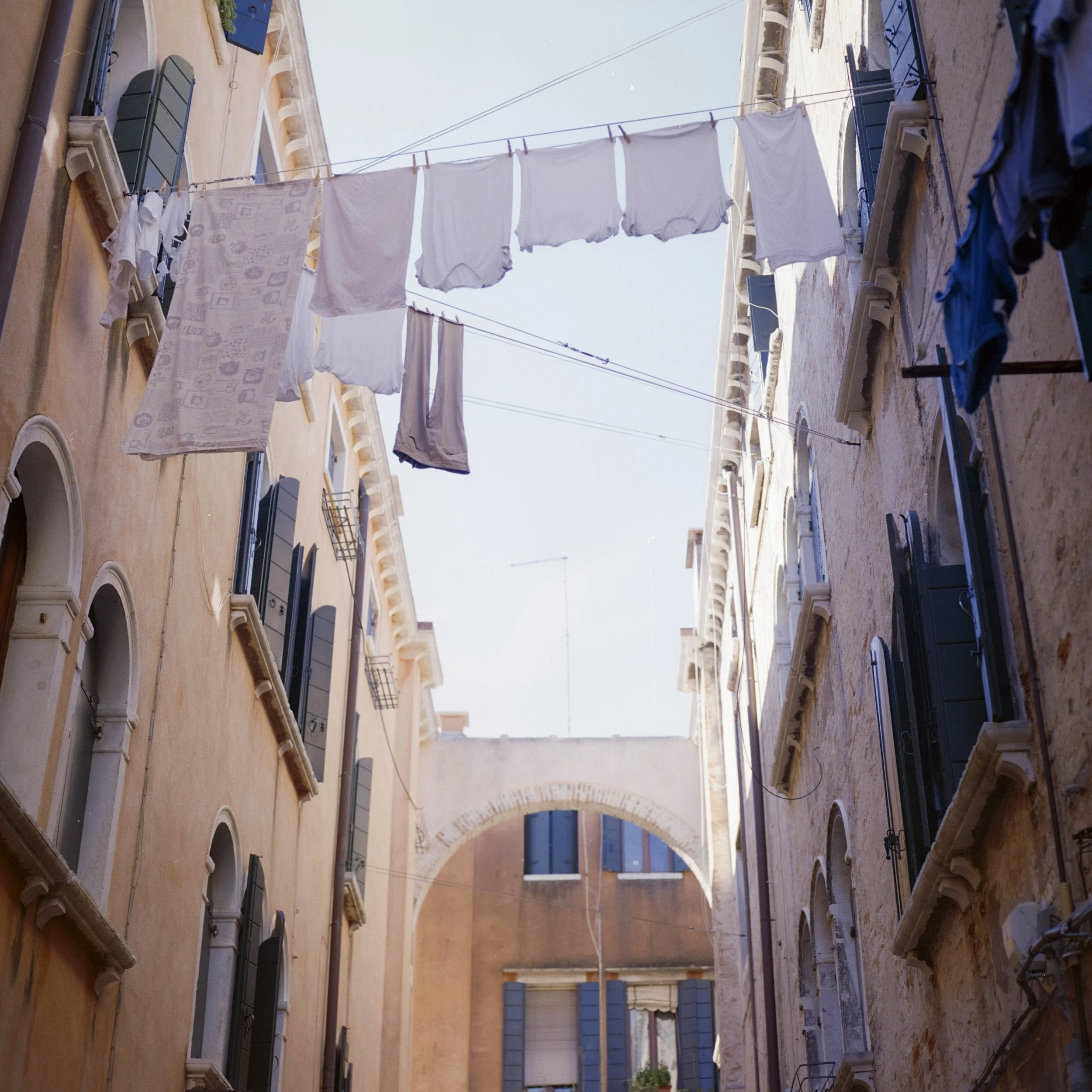 View of a building with laundry hanging on clotheslines between windows, with a clear blue sky overhead.