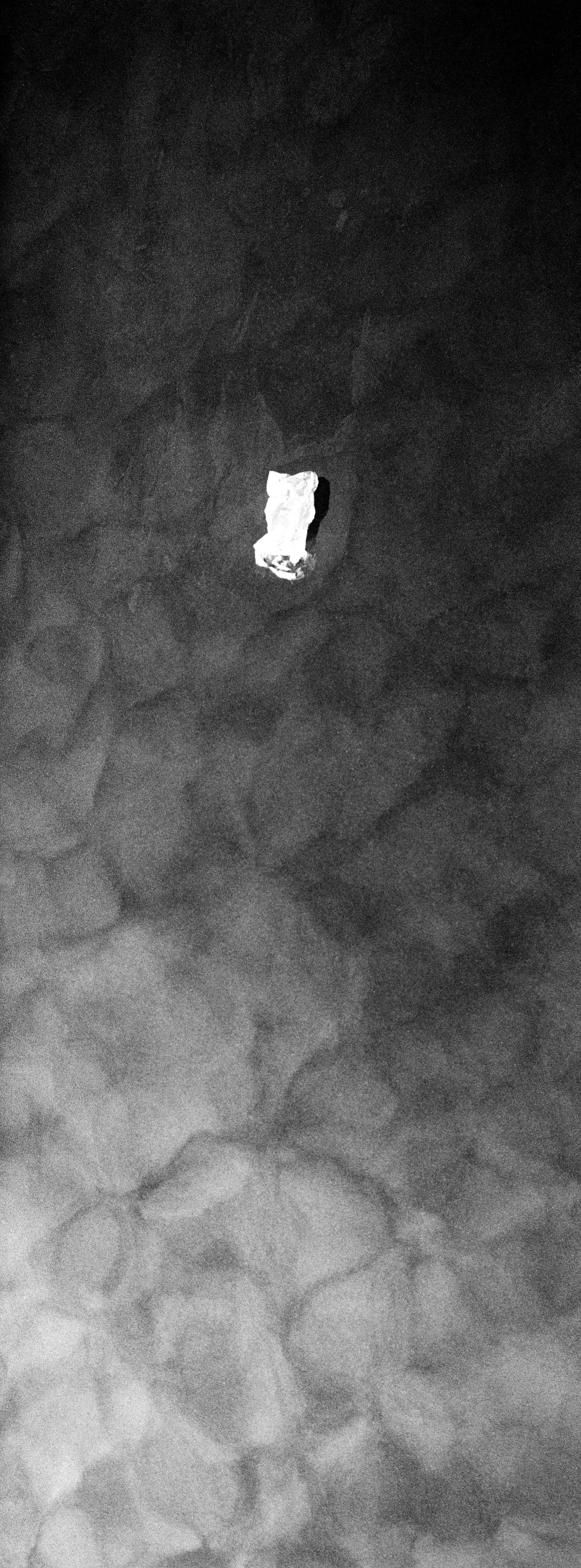 A crumpled piece of paper on a dark, textured surface with a gradient from light to dark.