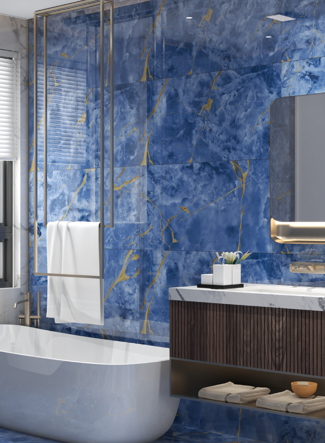 A modern bathroom with blue-tiled walls featuring gold veins, a white bathtub, a sink with a marble countertop and wooden cabinetry, a decorative plant, and windows with blinds.