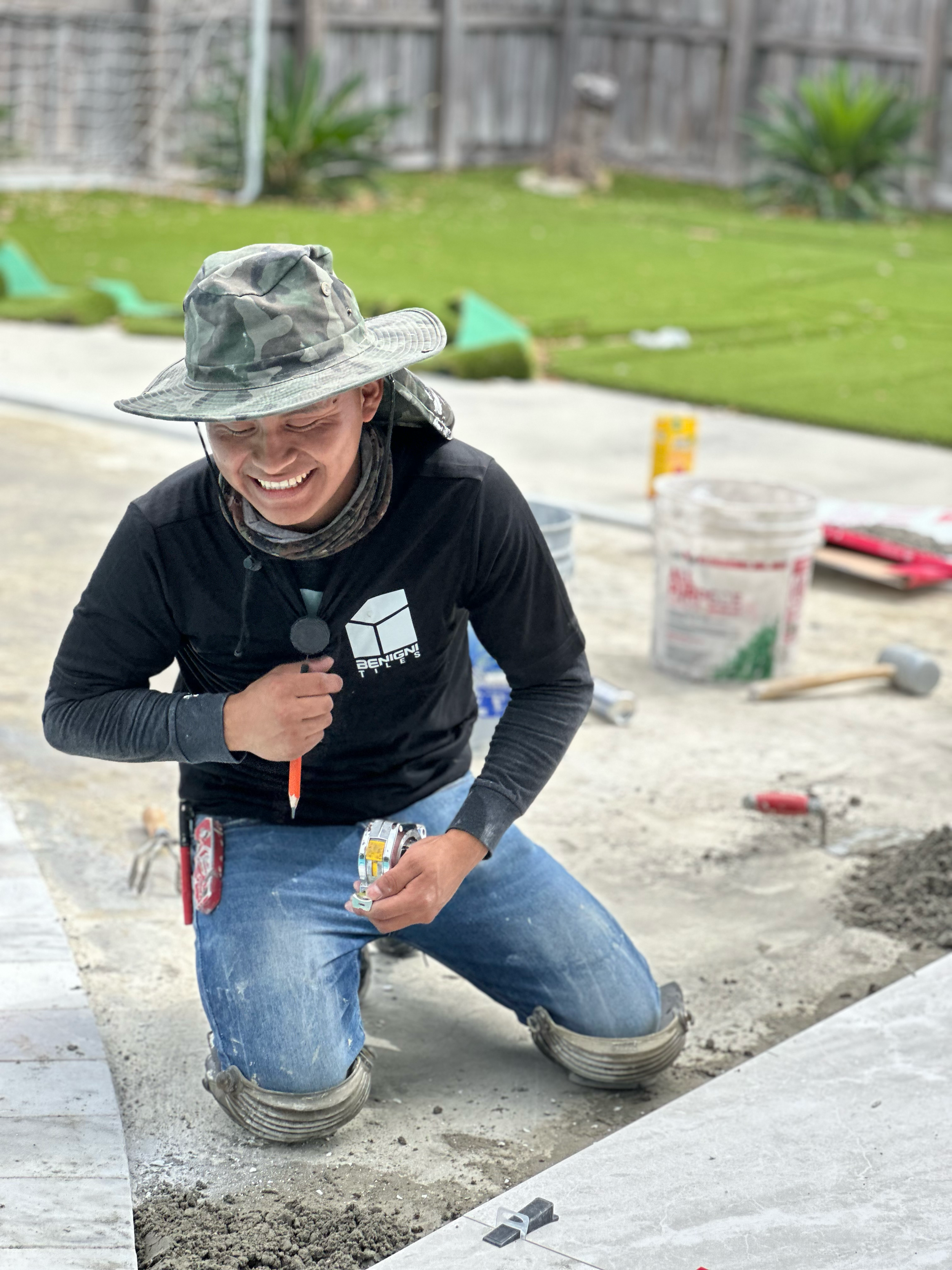 A man laying mosaic tiles on a construction site, wearing protective gear and using tools.