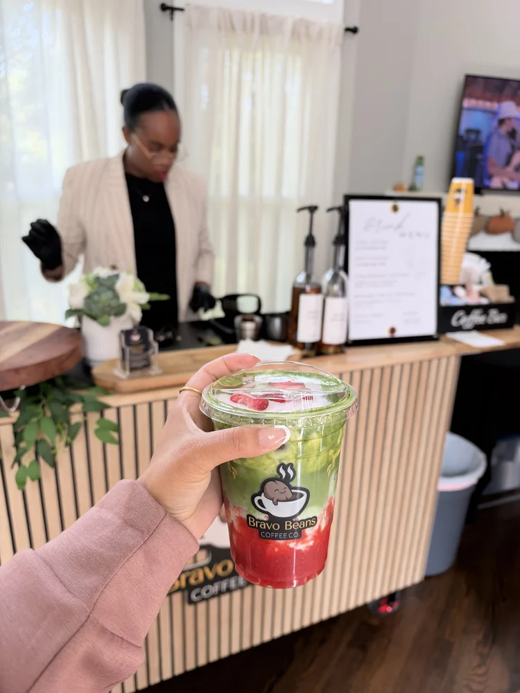 Guest holding a strawberry matcha in front of the Bravo Beans cart