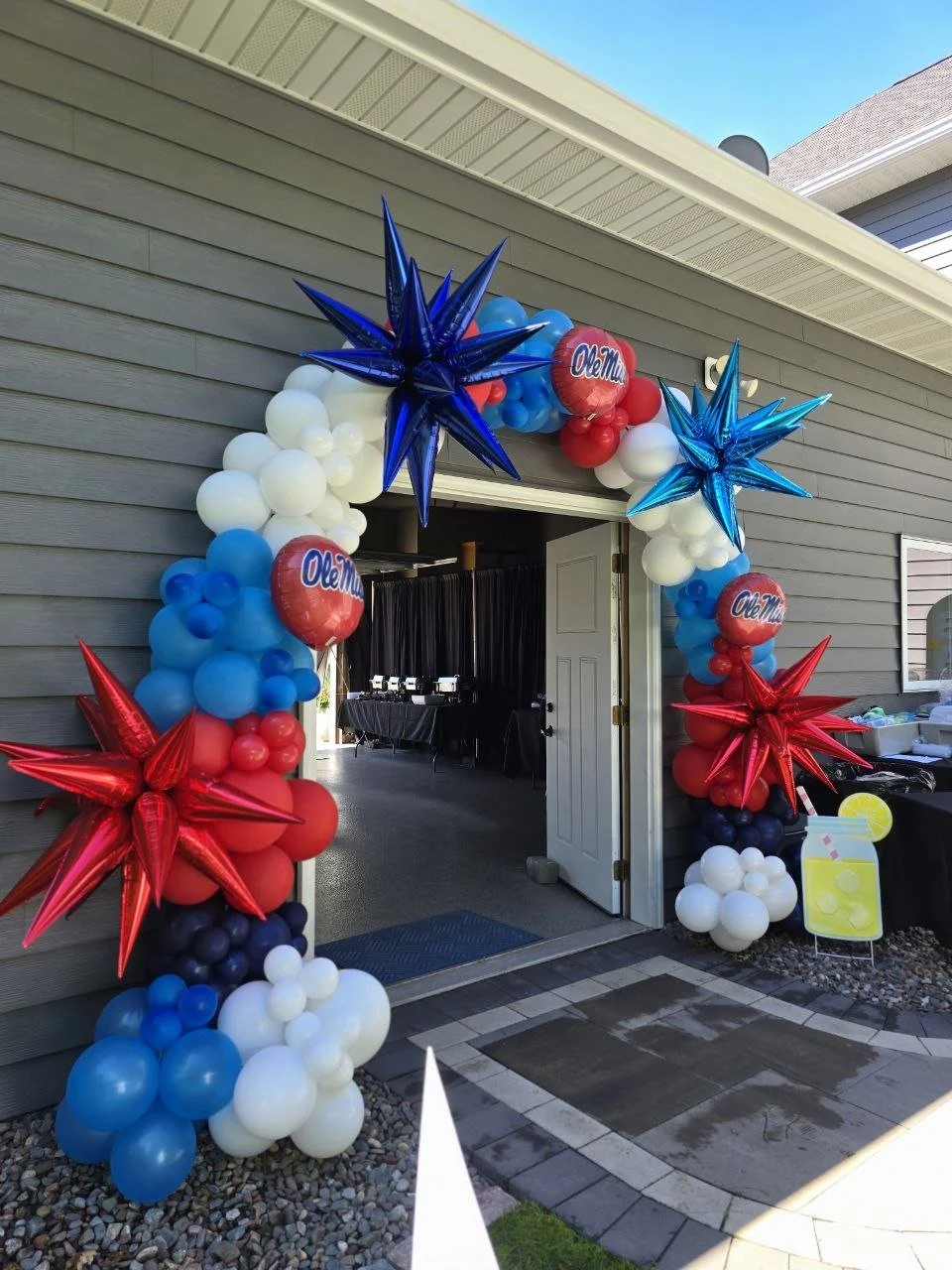 Decorative balloon arch with red, white, and blue balloons, including large shiny stars and round balloons, at an entrance, celebrating Ole Miss, an American university.